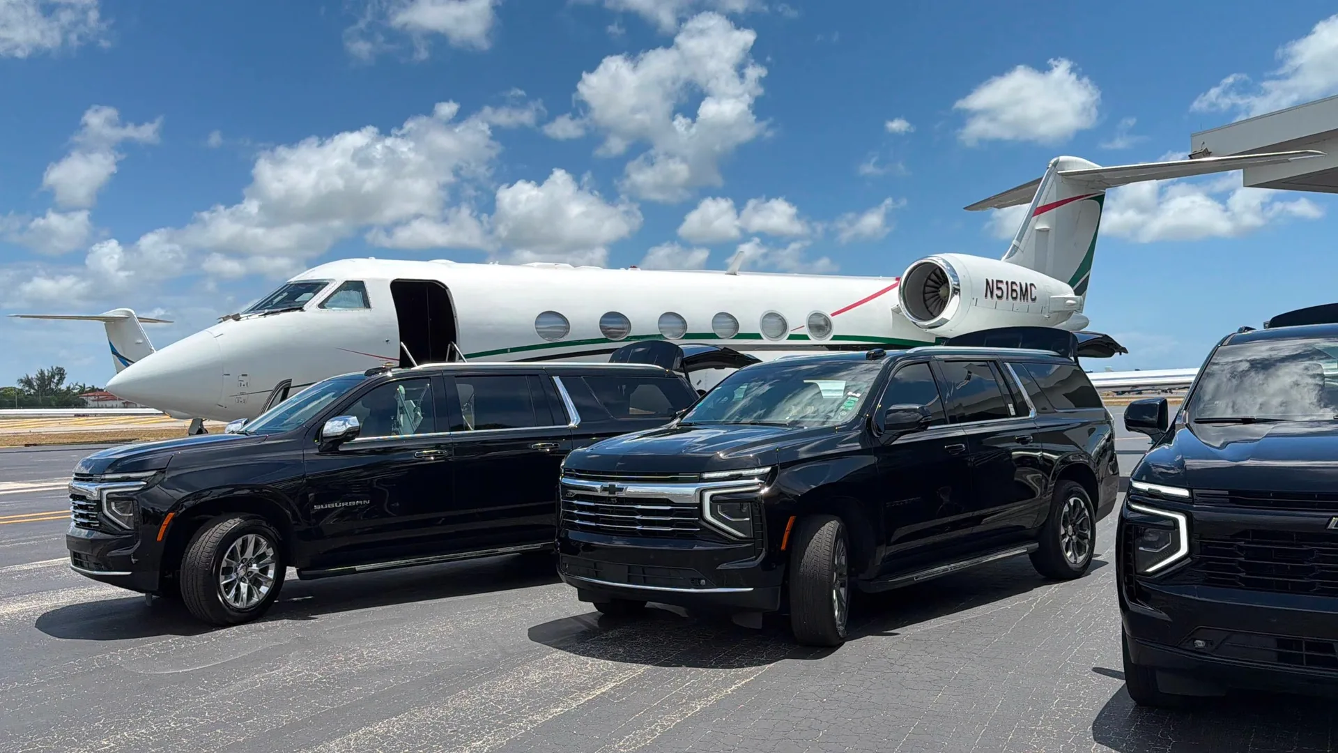 Row of black Chevrolet Suburban SUVs parked beside a white Gulfstream private jet on the tarmac