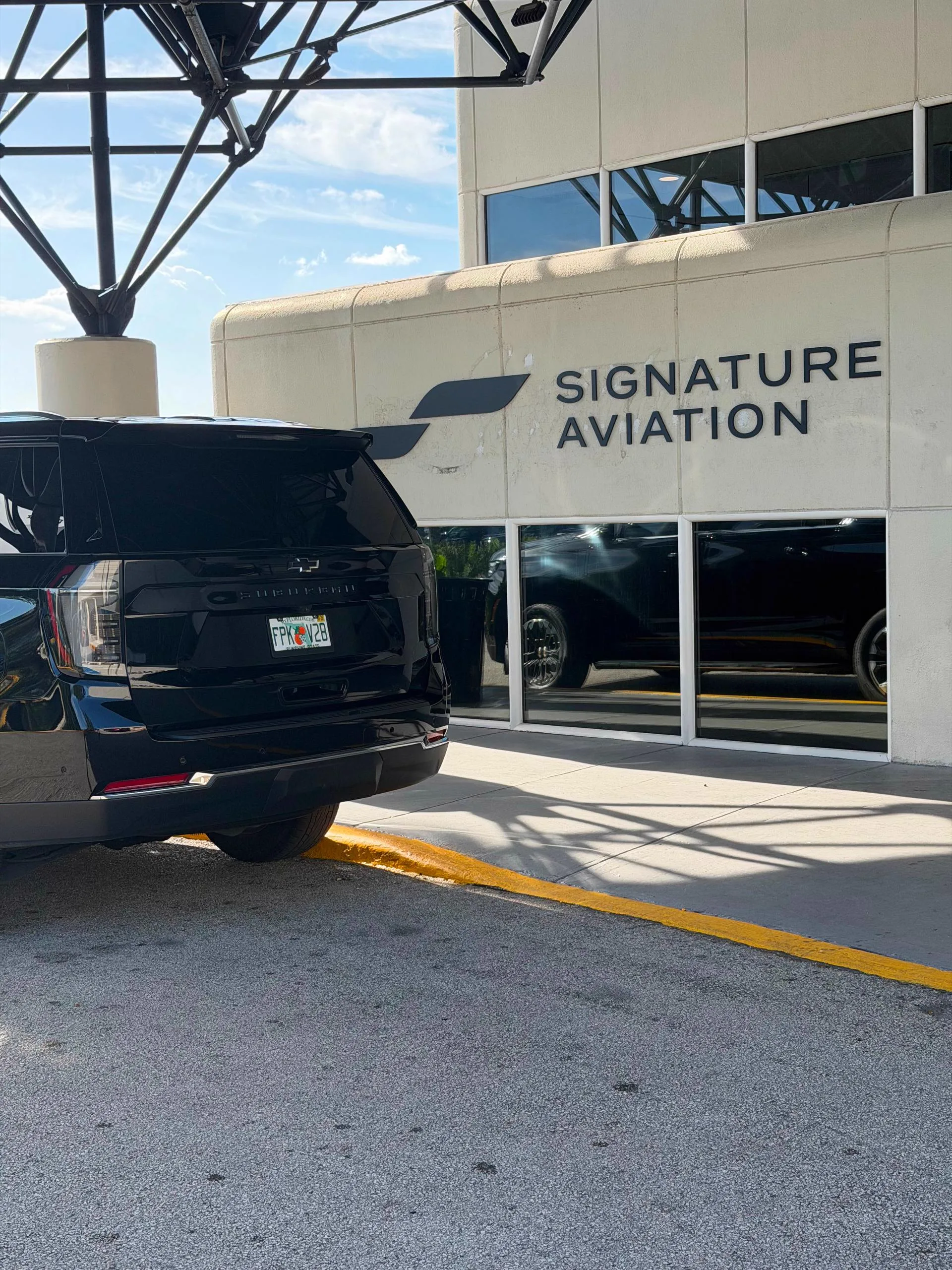 Rear view of a black SUV waiting at a private aviation terminal, ready for a chauffeured pickup