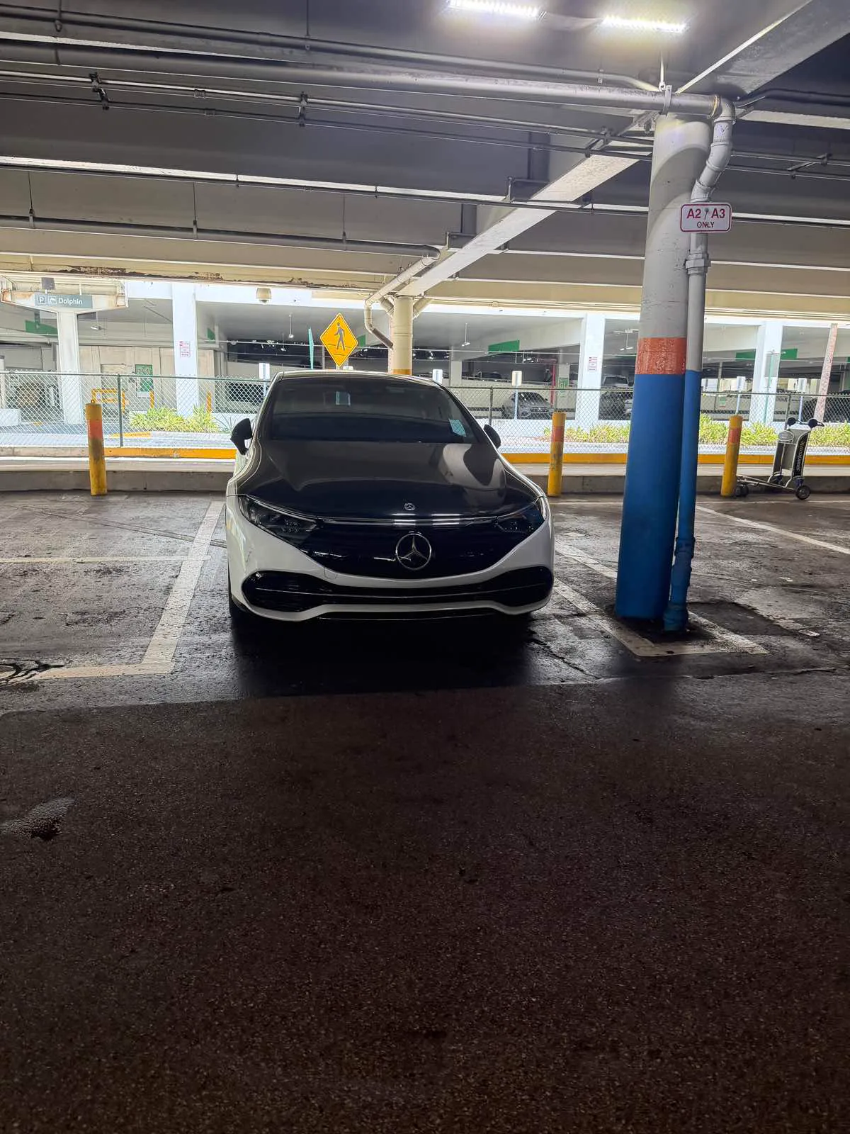 Front view of the white Mercedes-Benz EQS luxury sedan parked in the MIA airport garage, Best Ride Miami