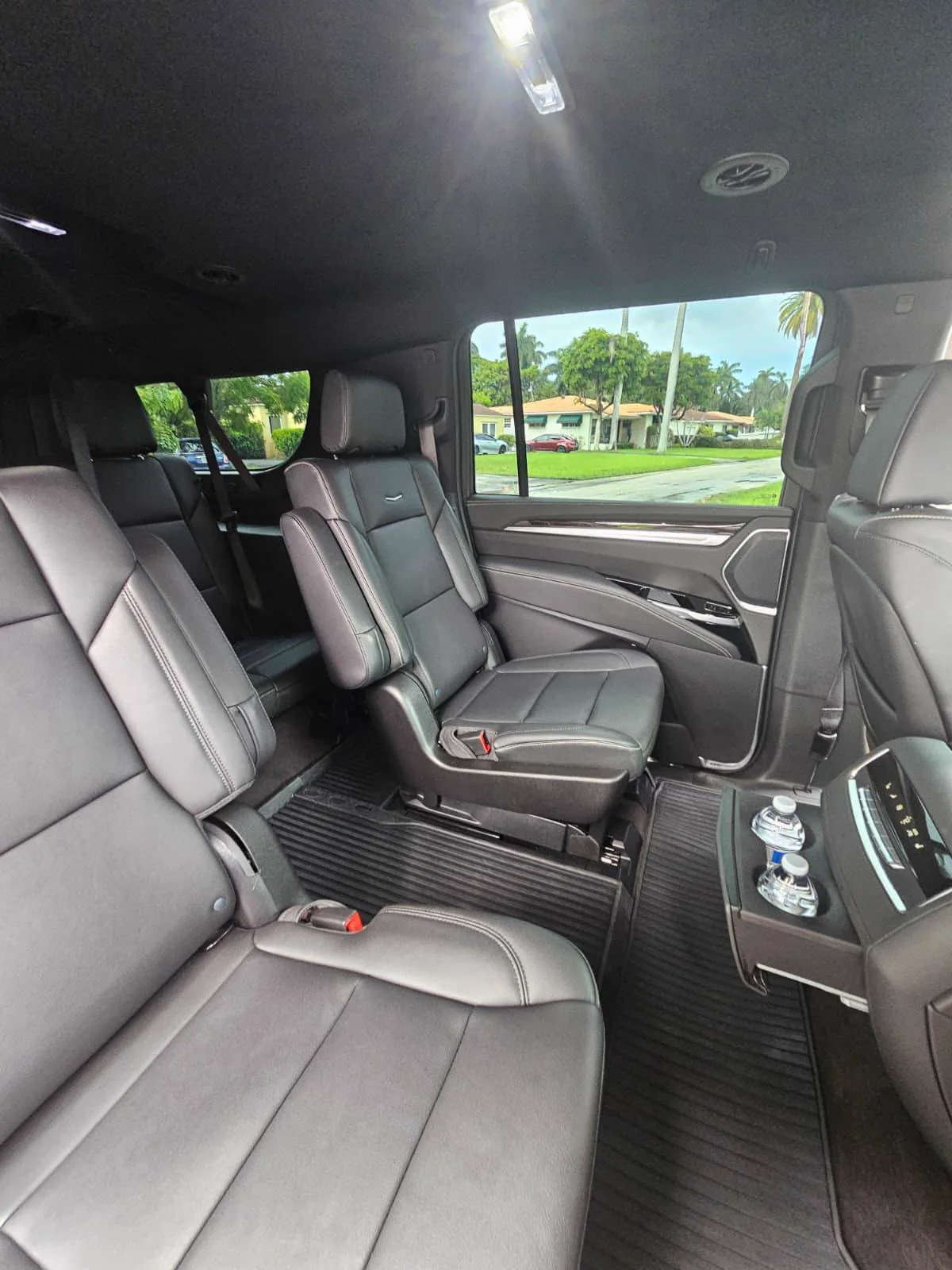 Two bottles of water in the center console between black leather rear seats of a Cadillac Escalade