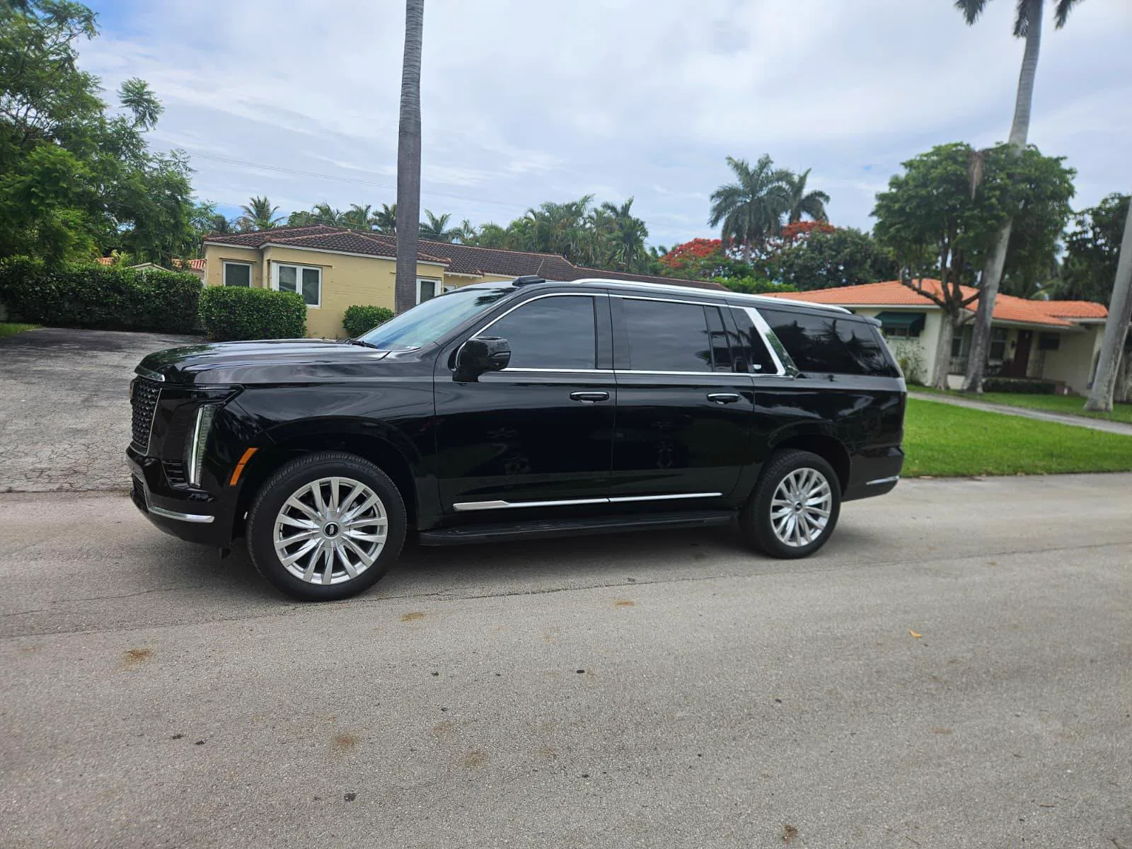 Black Cadillac Escalade with chrome wheels on a residential Miami street, the SUV behind our fixed fares