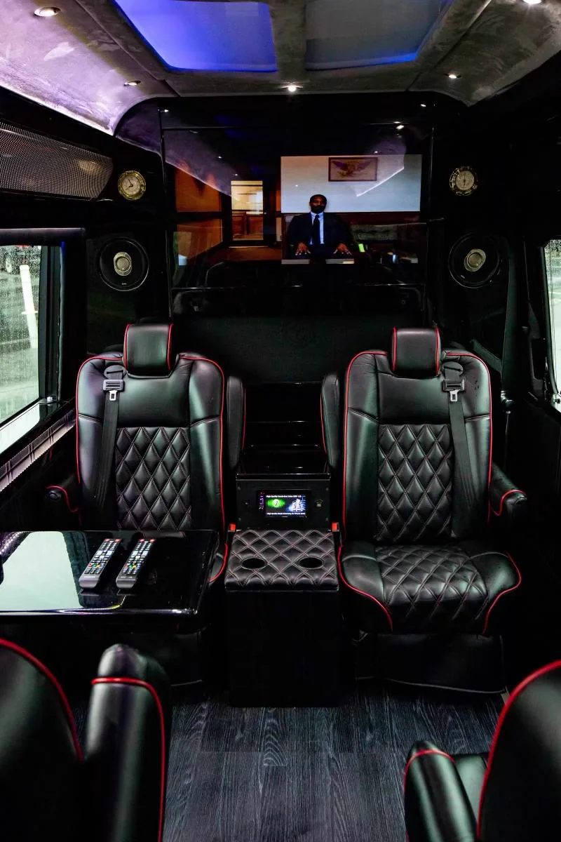 Front lounge of the Best Ride limo bus: red-piped quilted seats and wood floor