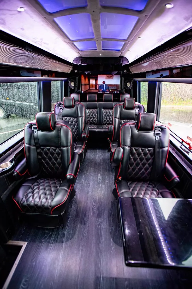 Wide limo bus cabin with quilted black leather perimeter seating piped in red, Best Ride Miami