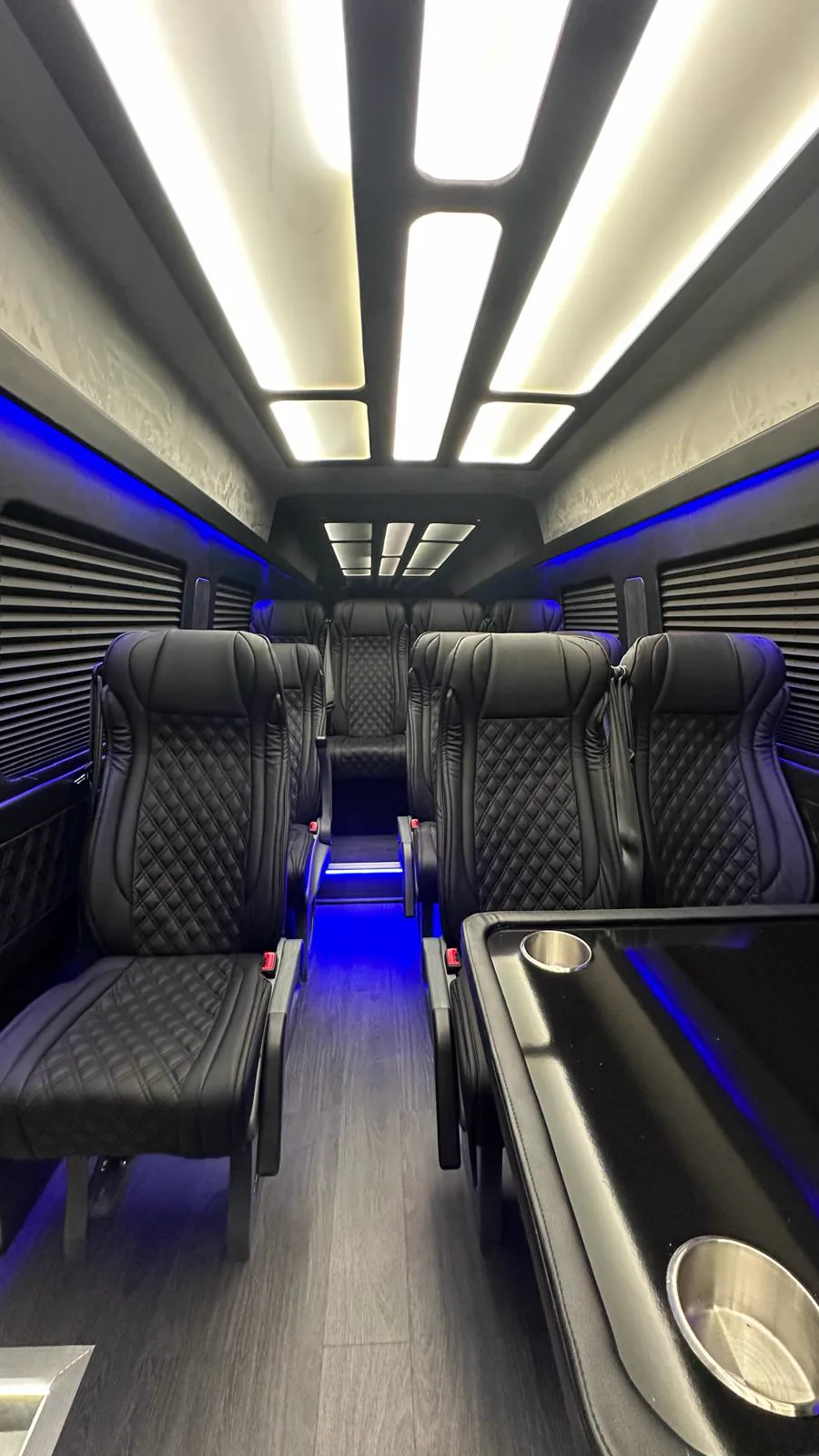 Shuttle cabin with warm white ceiling panels, blue LED side accents and quilted leather seats along the aisle